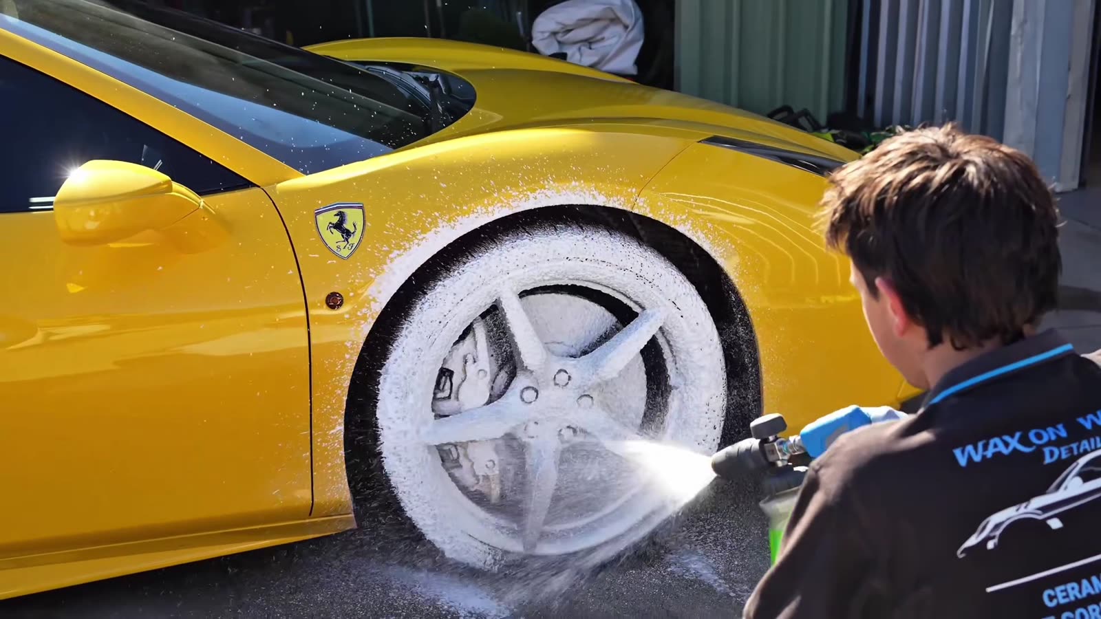 A Ferrari covered in snow foam during the decontamination wash that precedes a ceramic coating