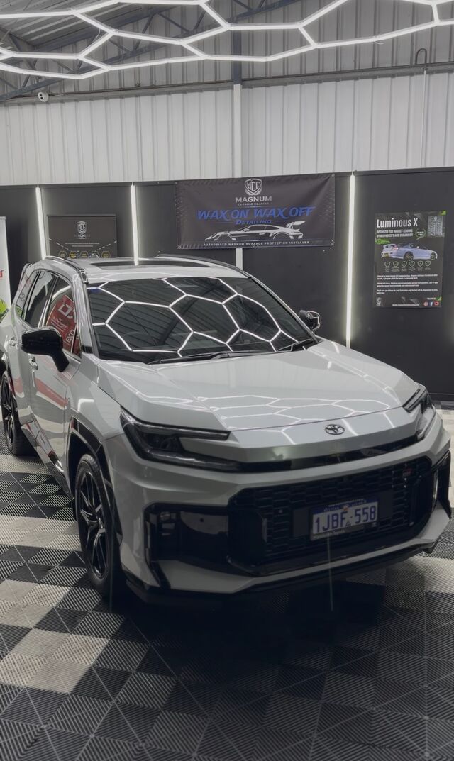 Front three-quarter view of a silver-grey SUV under the workshop lighting after paint preparation and coating