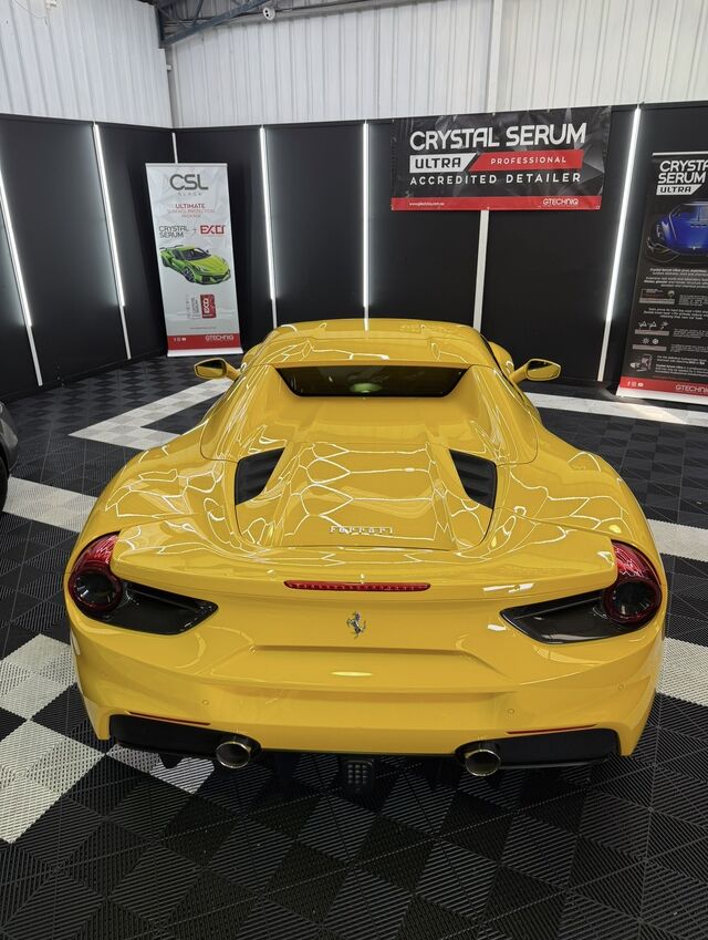 Rear view of a yellow mid-engined supercar, its corrected and coated paintwork holding a deep, even reflection